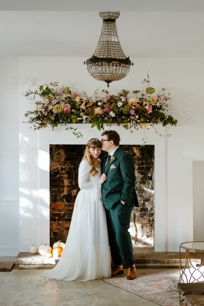 bride and groom standing in front of fireplace